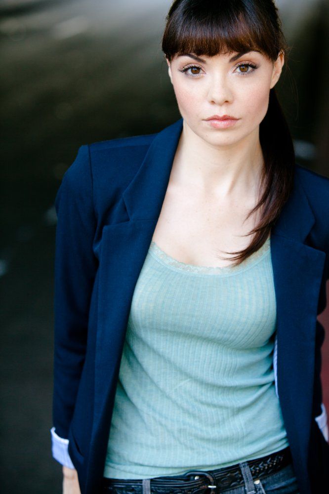 Annemarie Pazmino with a bangs while wearing a blue coat, light blue inner blouse, black belt, and denim pants